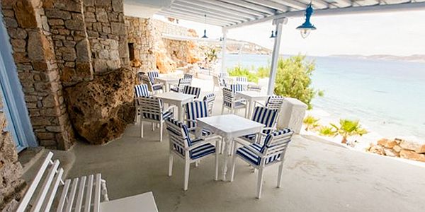 Outdoor seating area under a trellis overlooking the blue sea